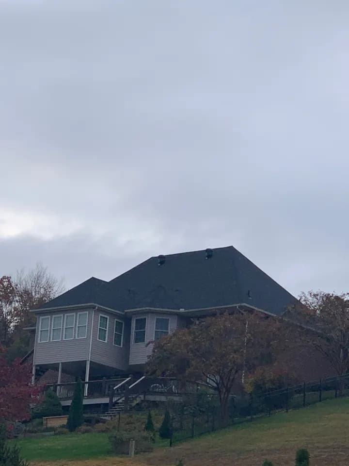 Two-story house on a hillside with a charcoal shingle roof replacement, Kingston