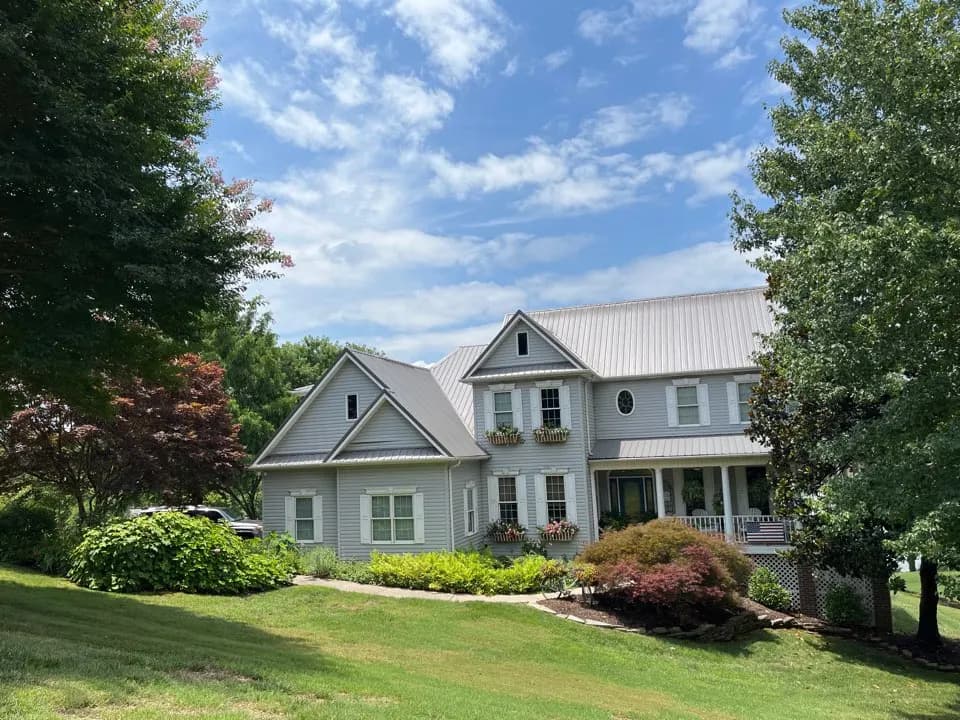 Two-story gray house with a silver metal roof and dormers, from a Kingston metal roof repair