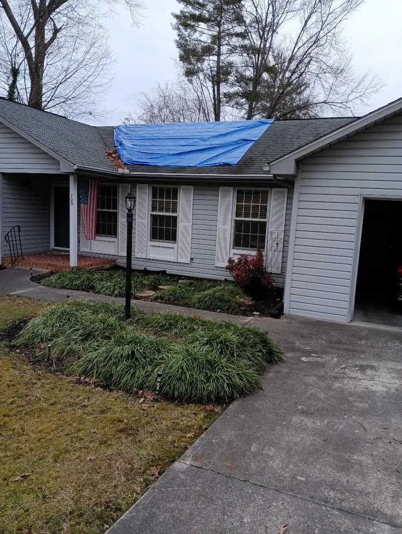 Blue tarp over a shingle roof leak on a home in Clinton