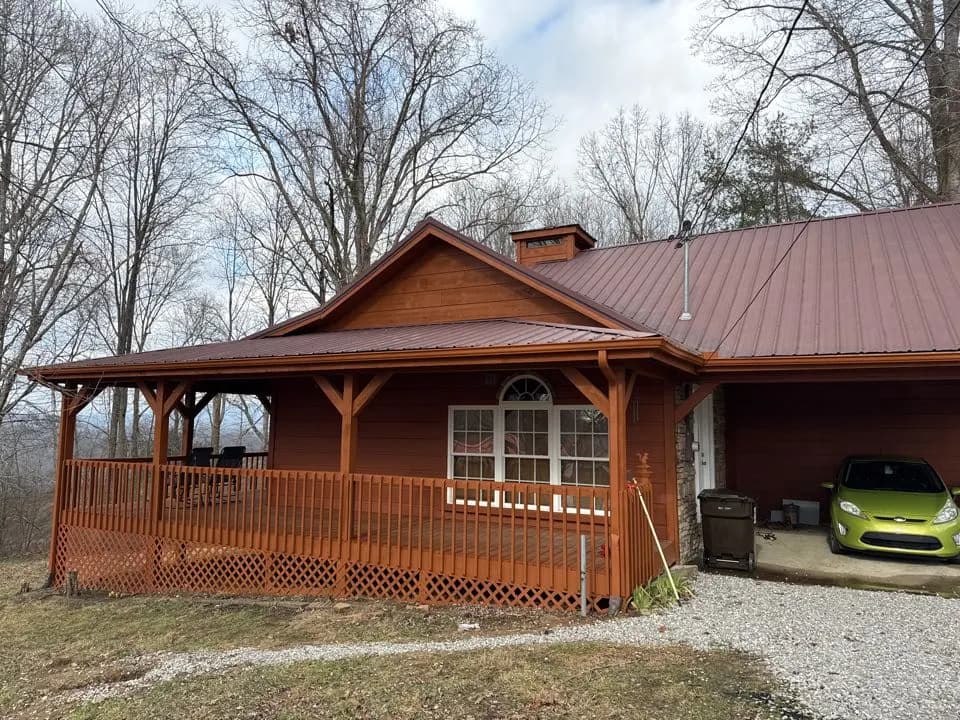Brown house with a wraparound porch and a brown metal roof, from a Harriman metal roof repair