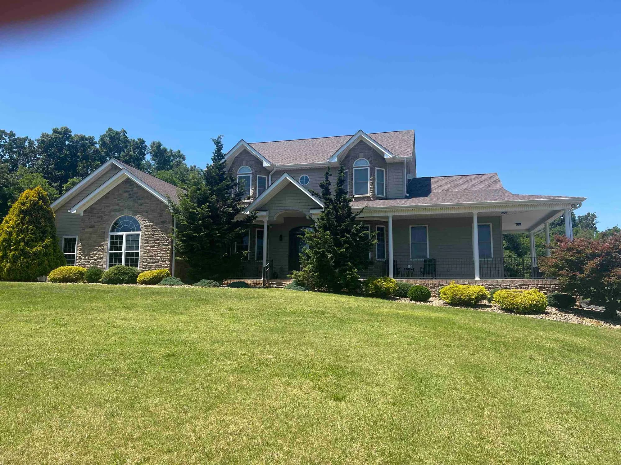 Two-story brick and siding home with a shingle roof and a landscaped front lawn in Lenoir City, photographed at a roof replacement