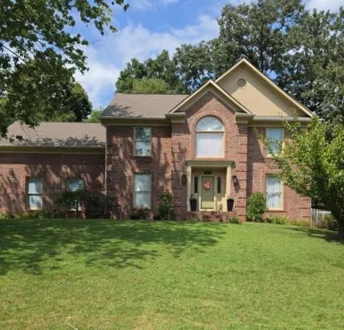 Brick two-story house with an arched window and a green lawn, Knoxville