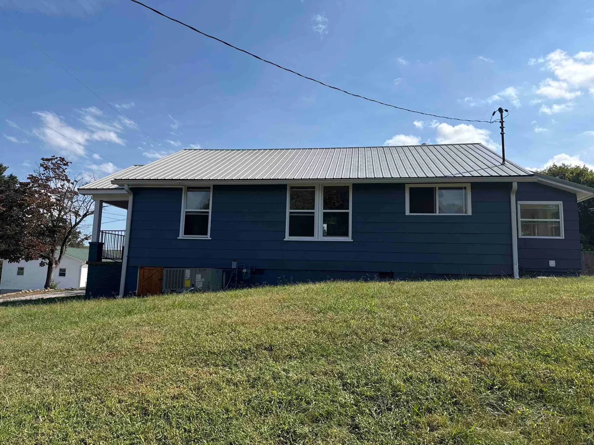 Single-story blue home in Loudon with a metal roof, visited while answering a homeowner's metal roof questions