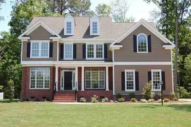 Two-story brick and tan siding house with a shingle roof and front lawn