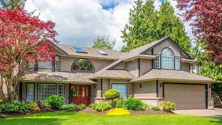 Large two-story house with a shingle roof and landscaped front yard