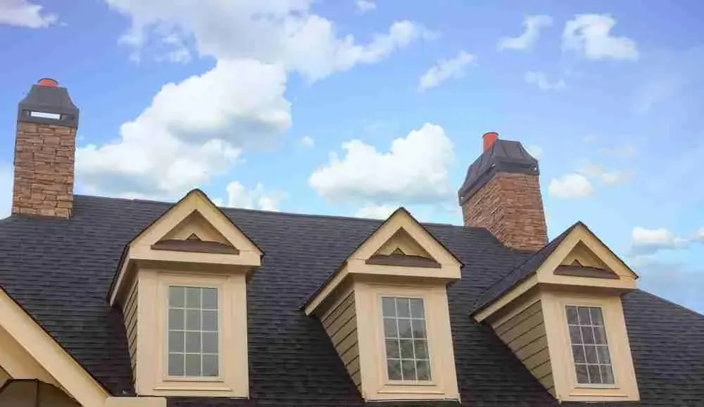 Shingle roof with three dormers and two brick chimneys