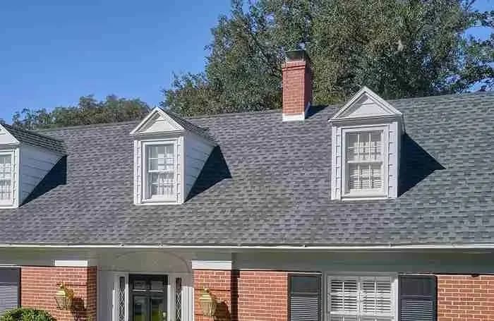 Shingle roof with dormers and a brick chimney on a brick house