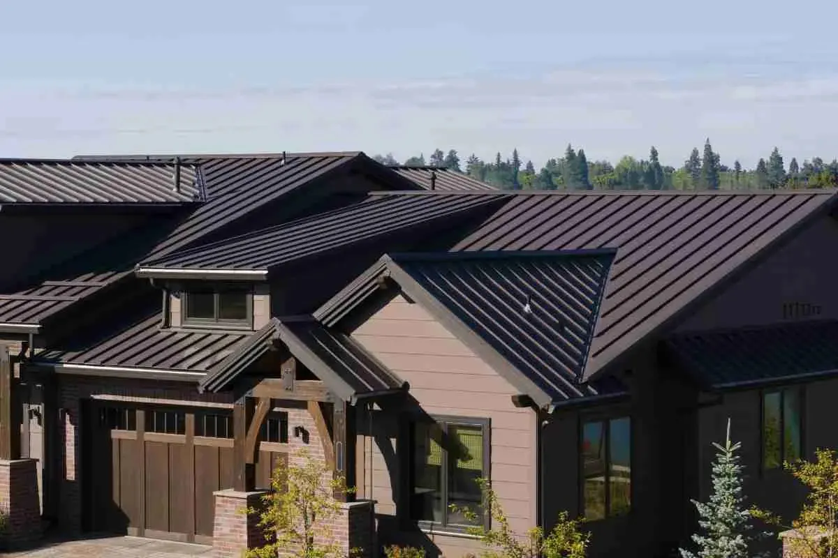Brown house with a dark standing seam metal roof over the garage and entry
