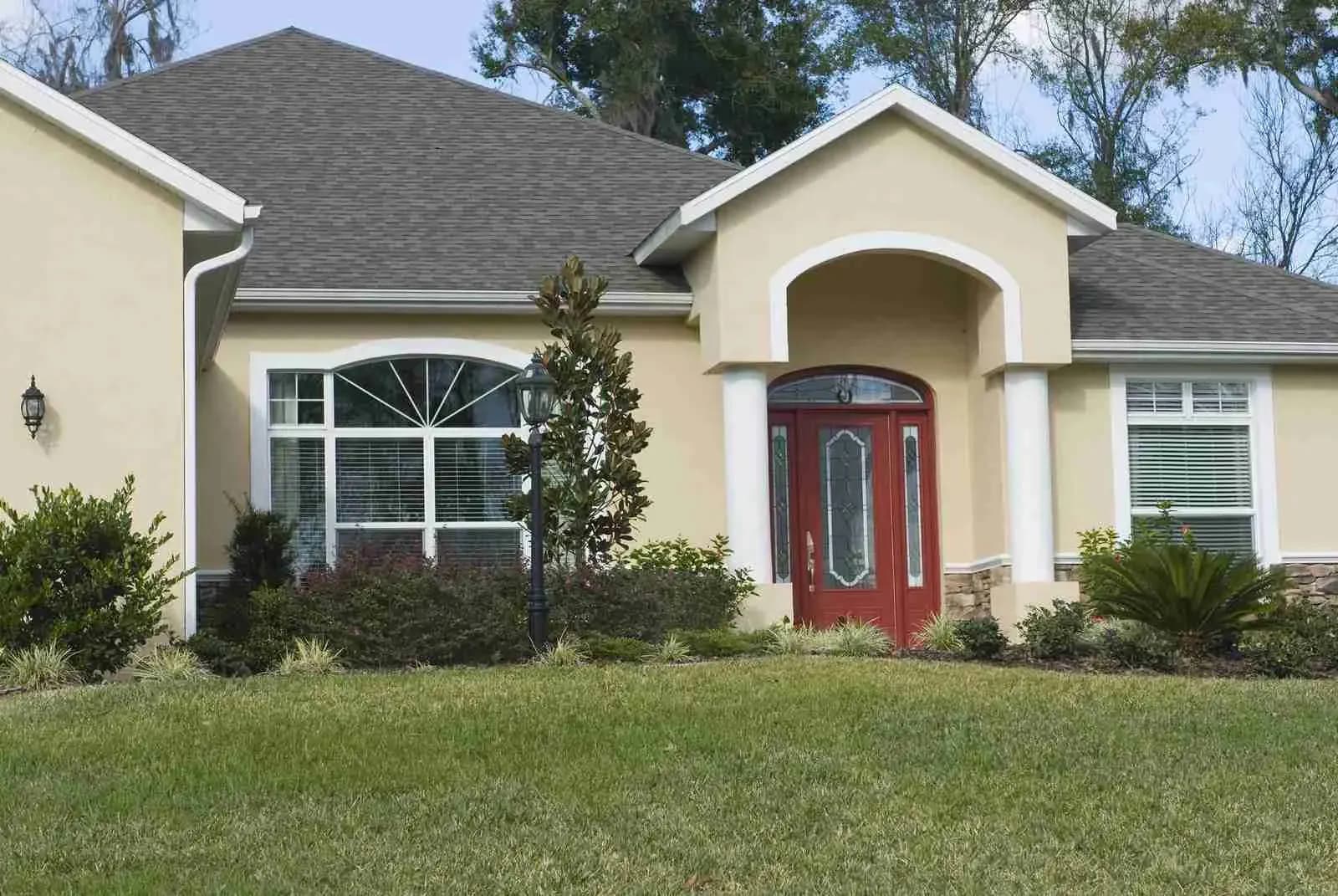 Stucco house with a shingle roof, arched entry, and red front door