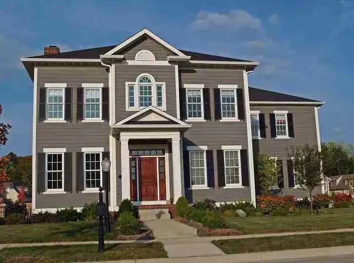 Two-story gray colonial house with black shutters and a red front door