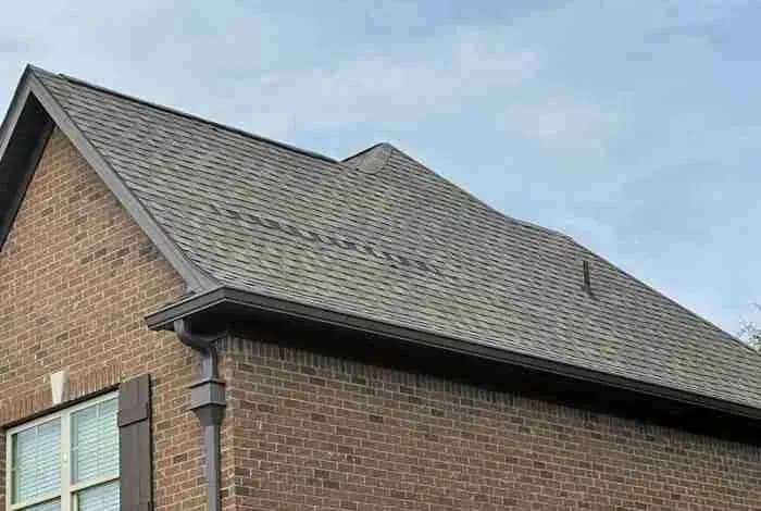 Brick house with a dark shingle roof and gutter