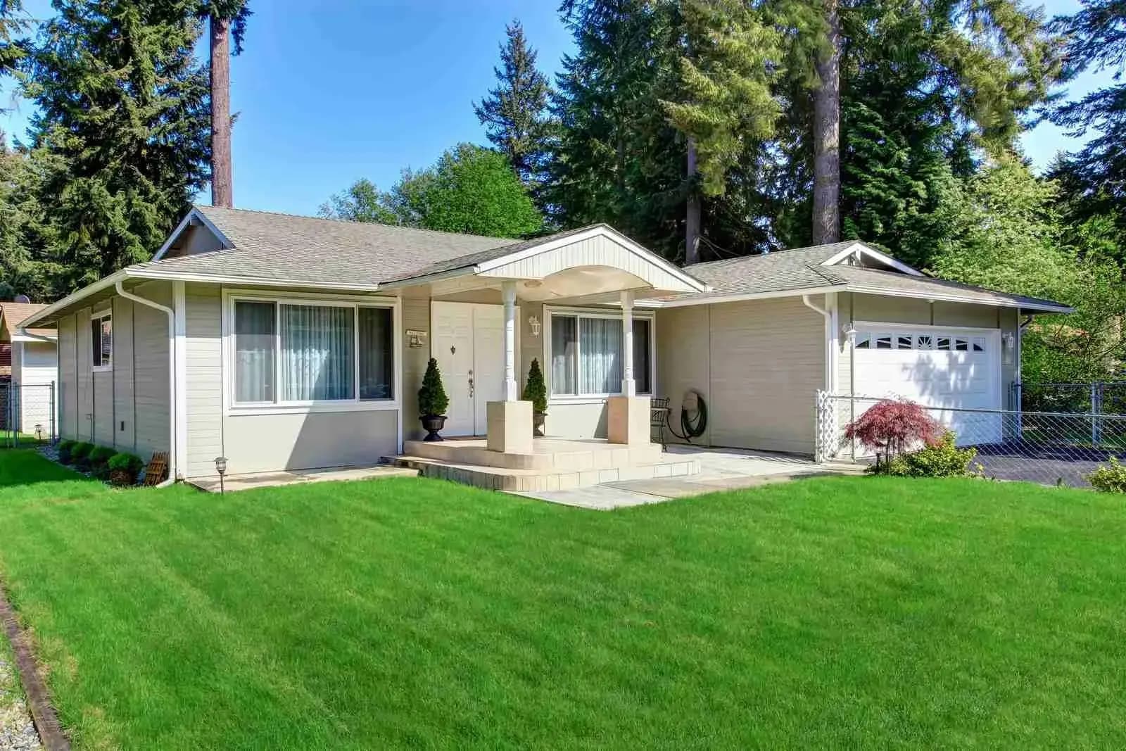 Single-story ranch house with a shingle roof and green lawn