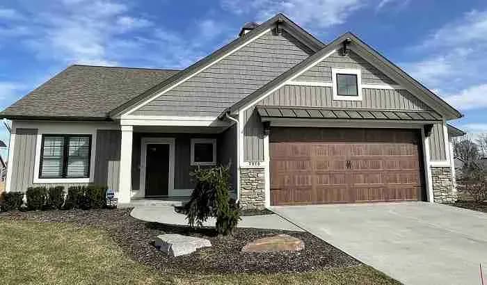 Gray single-story house with shake siding and a brown garage door