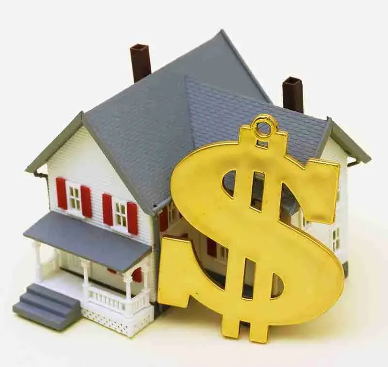 Model house next to a large gold dollar sign