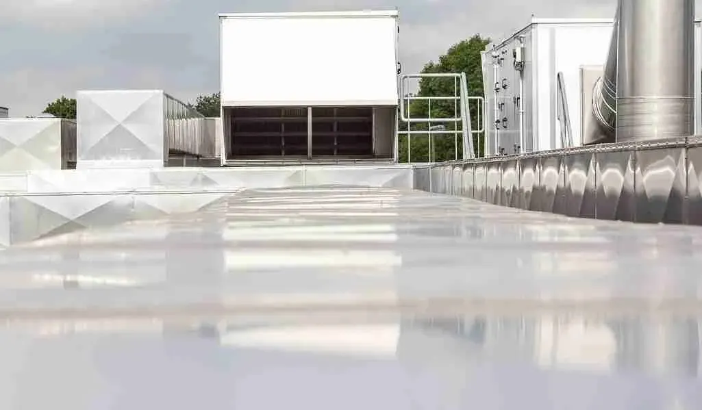 Wet white membrane on a commercial flat roof with rooftop equipment