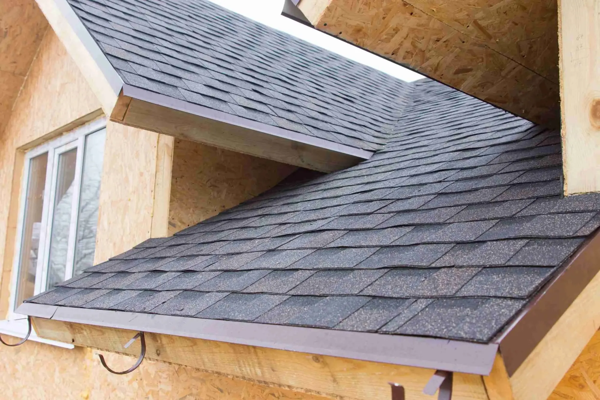 Close view of a new dark shingle roof edge on a house under construction