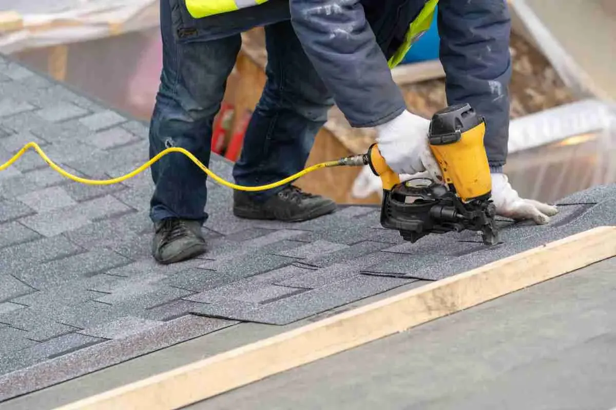 Roofer using a nail gun to install shingles