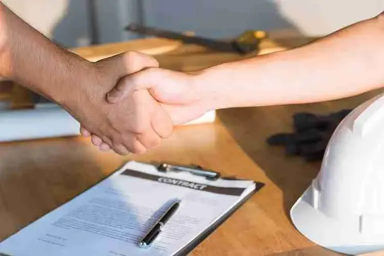 Handshake over a roofing contract and a white hard hat