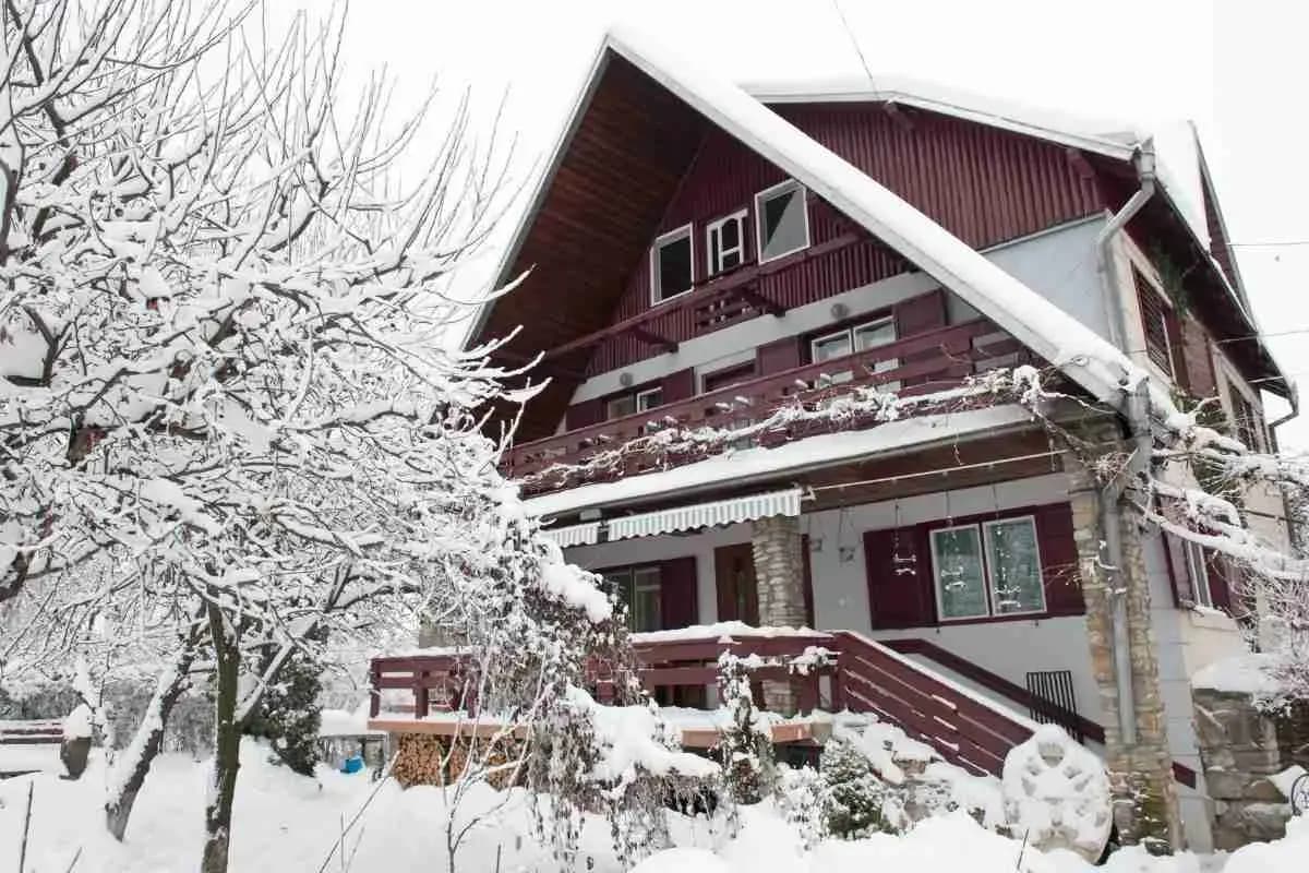 Snow-covered red chalet-style house and trees