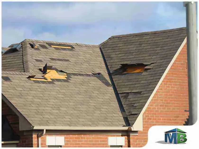 Storm-damaged shingle roof with missing shingles and exposed decking