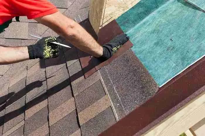Roofer installing shingles over green underlayment