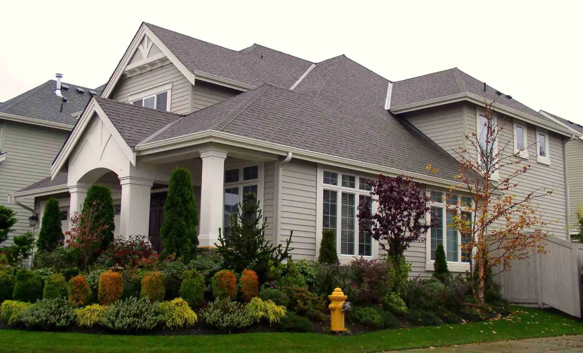 Large two-story house with a gray shingle roof and landscaped yard