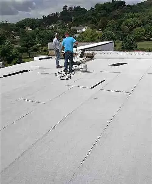 Two workers on a flat roof during a commercial roofing job