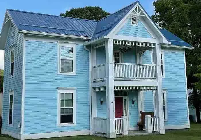 Light blue two-story house with a blue metal roof and double porch