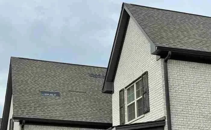 White brick house with a gray shingle roof