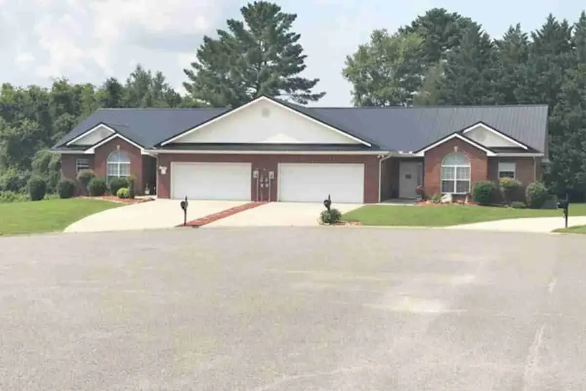 Brick duplex with a shingle roof and a wide paved drive