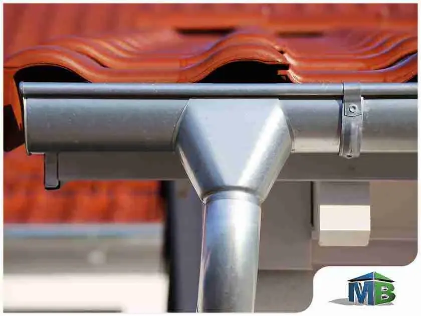 Metal gutter and downspout connection under a tile roof