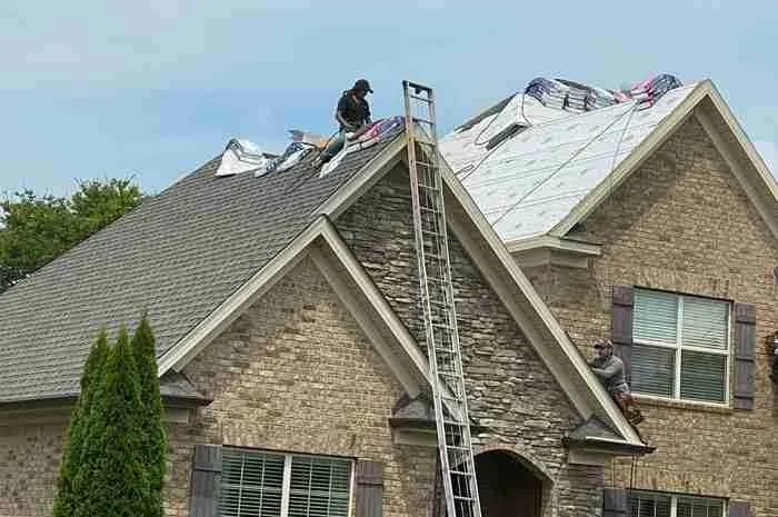 Roofers replacing the roof on a stone and brick house