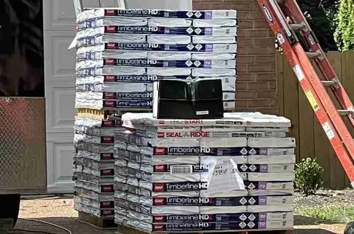 Pallets of GAF Timberline HDZ shingle bundles by a house with ladders