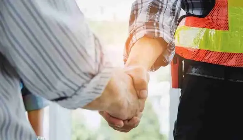 Handshake between a homeowner and a worker in a safety vest