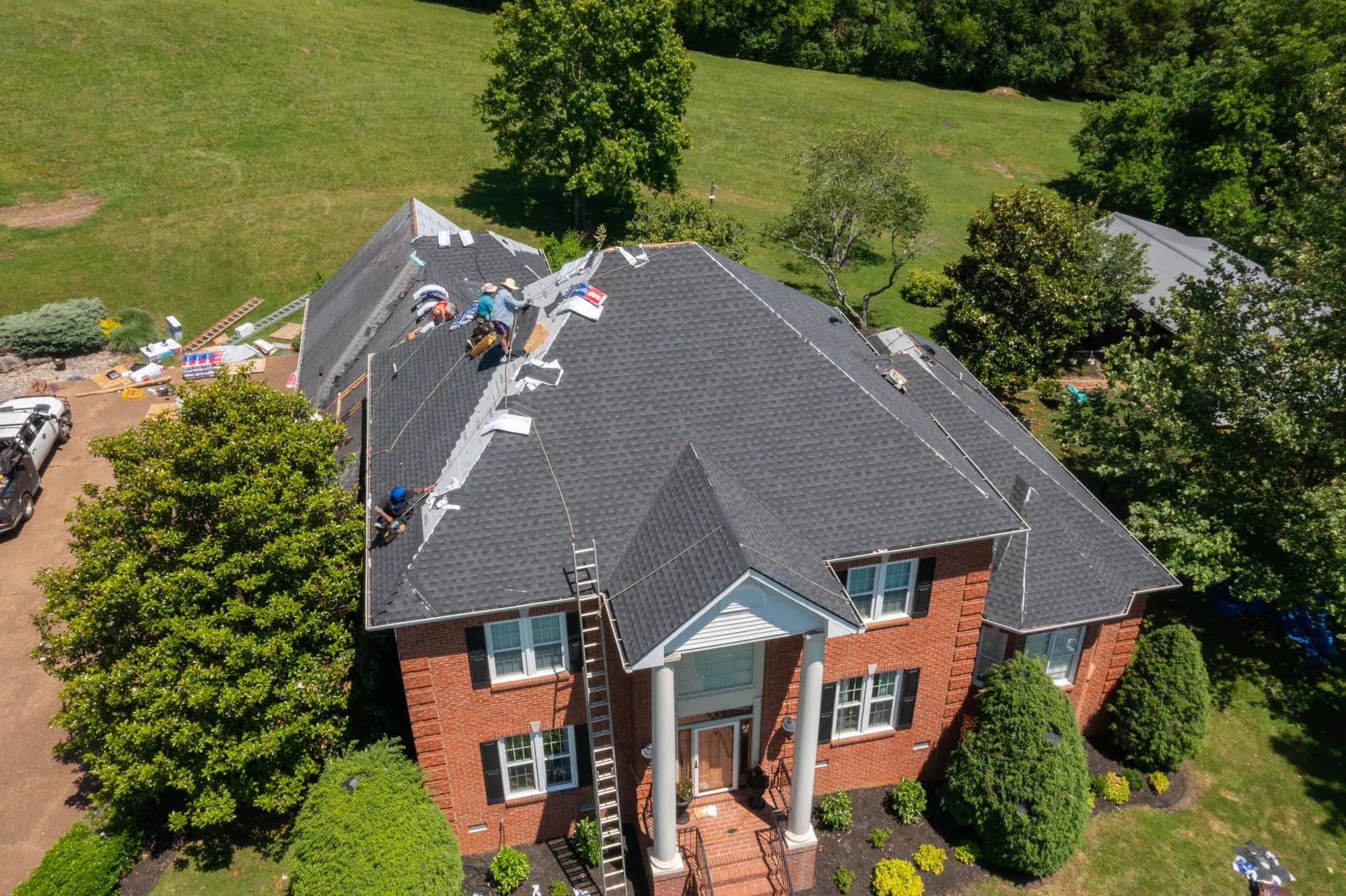 Aerial view of a brick house during a shingle roof replacement