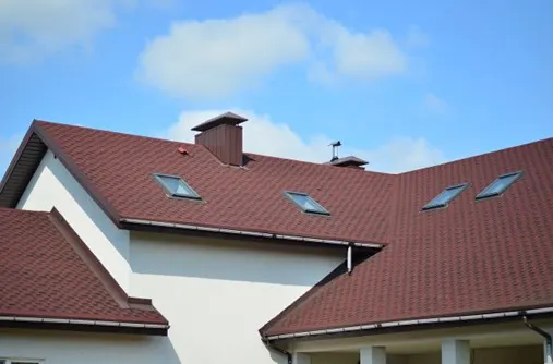 Red shingle roof with skylights on a white house
