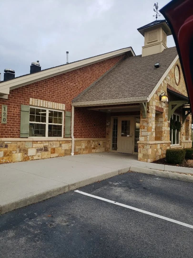 Single-story brick and stone office building with a shingle roof and parking lot