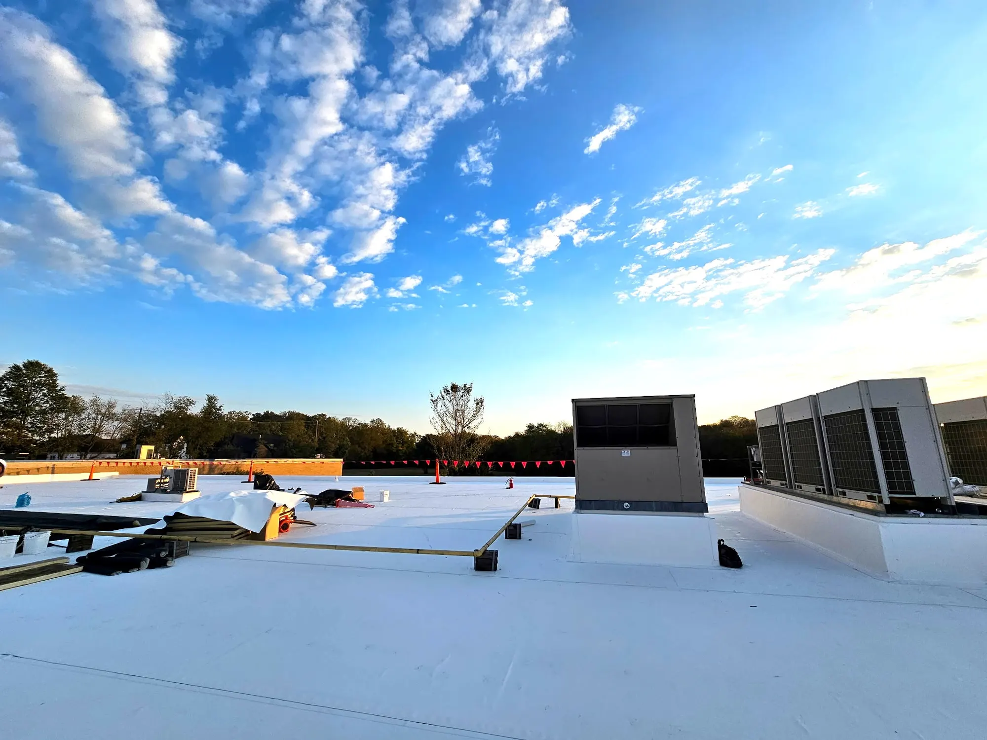 White single-ply commercial roof with rooftop HVAC units under a blue sky