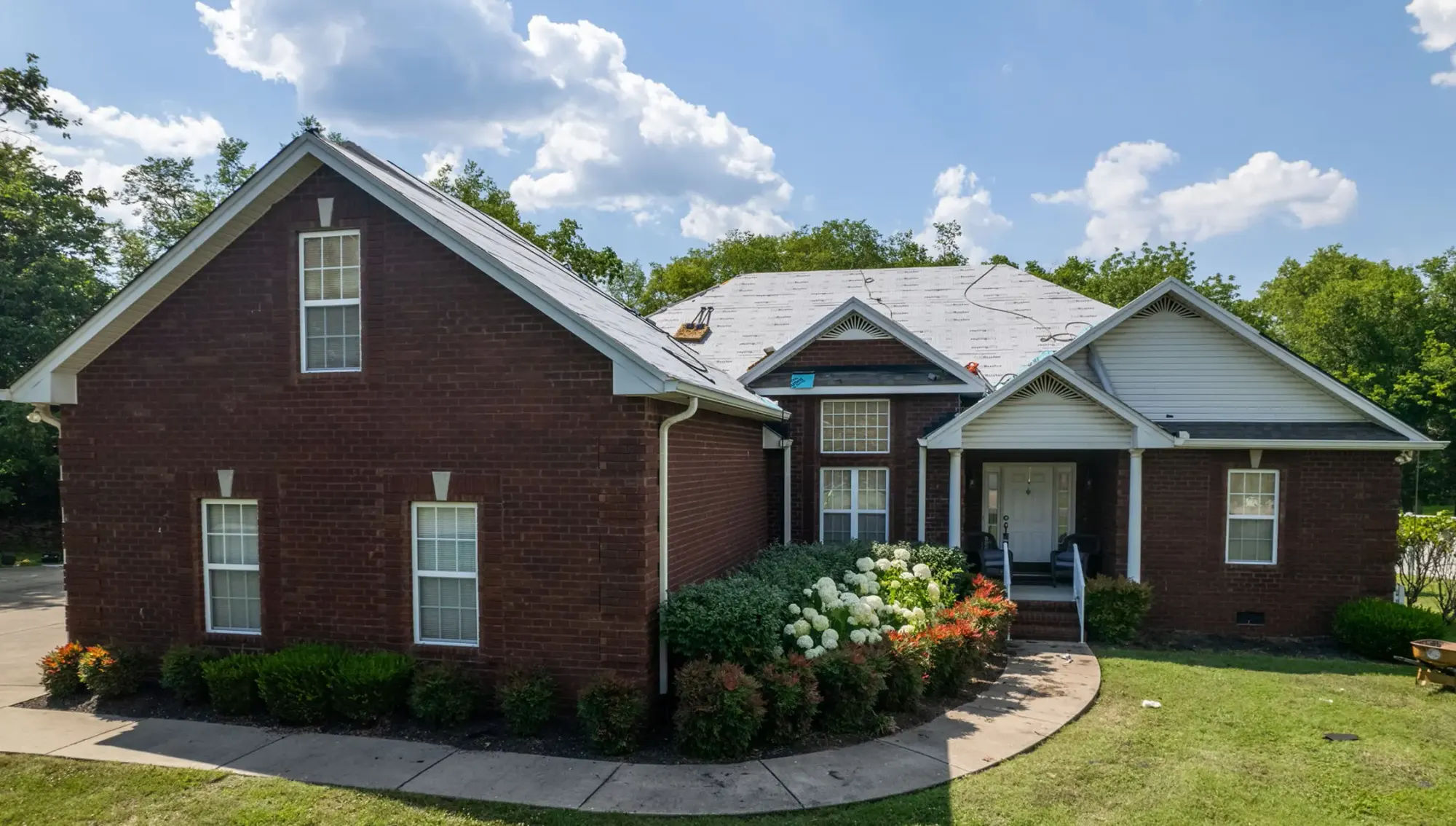 Brick home with a gray shingle roof and a covered front entry