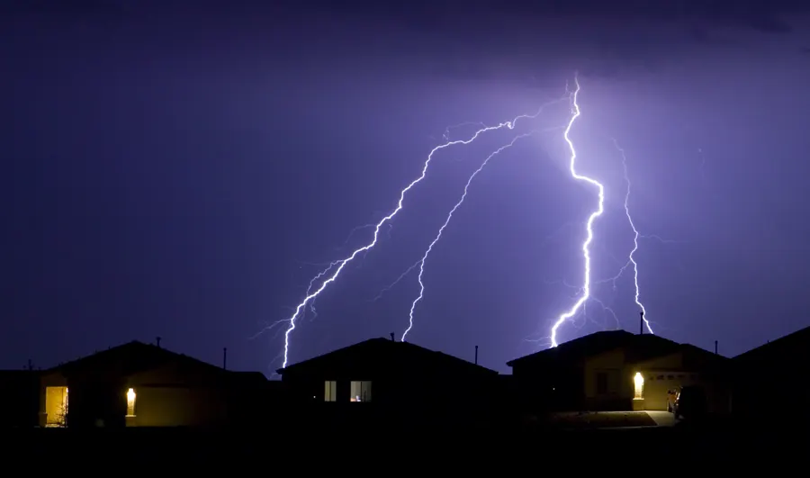 Lightning striking over a row of houses at night