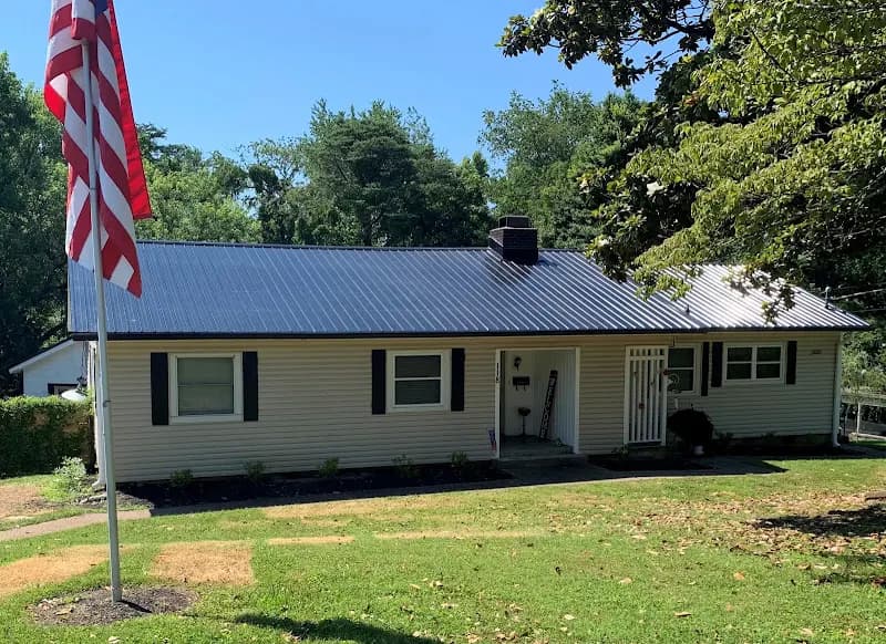 Single-story house with beige vinyl siding and a newly installed dark metal roof