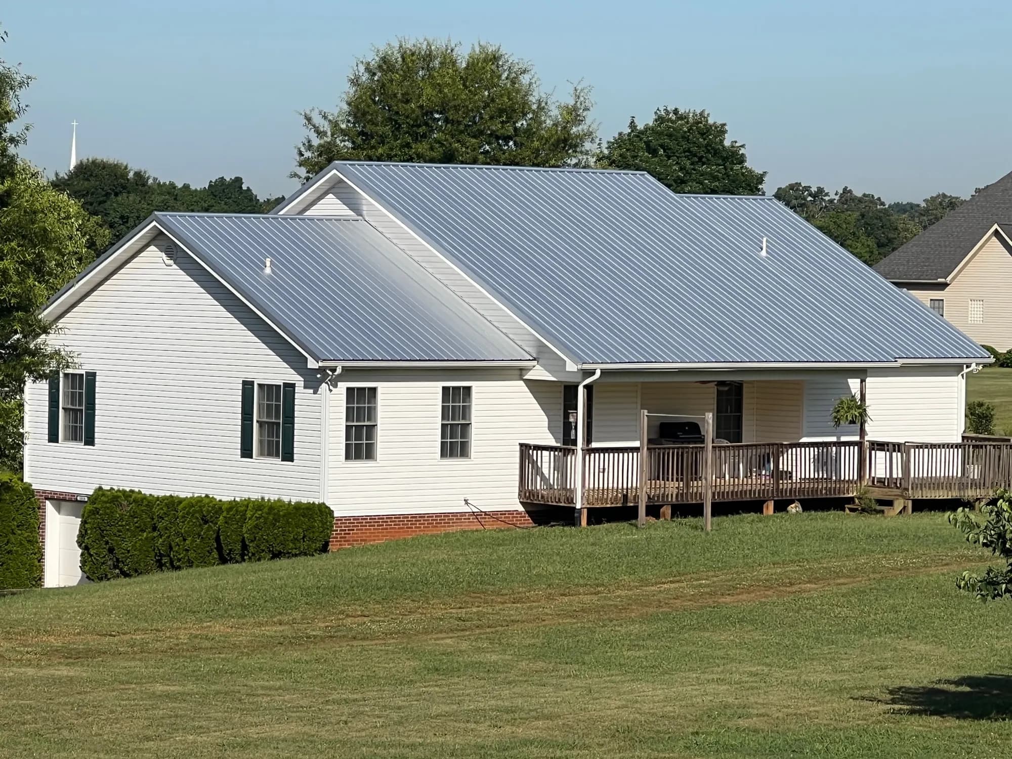 Single-story white home with a newly installed exposed fastener metal roof and a covered back porch, from our Knoxville office's job photos