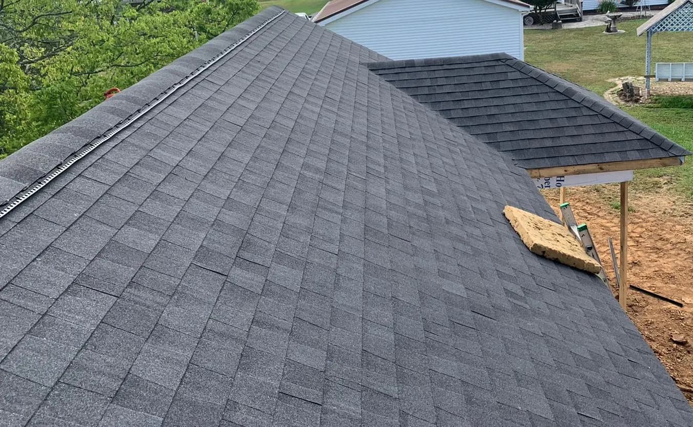 Aerial view of a newly installed dark gray asphalt shingle roof on a residential home with a nearby garage roof