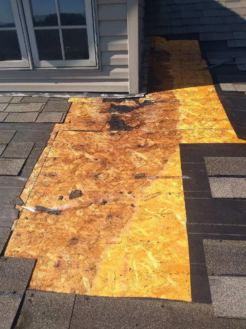 Exposed plywood roof decking near a dormer with shingles and underlayment removed during a roof repair