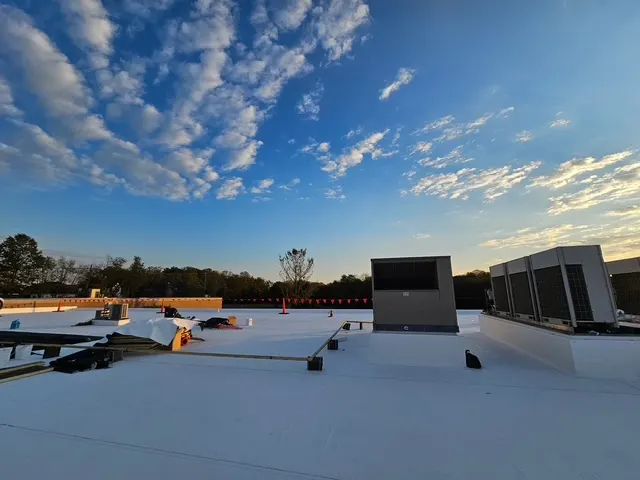 White TPO membrane roof on a commercial building with rooftop HVAC units under a blue sky