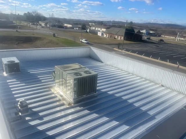 New light gray metal roof on a commercial building with two rooftop HVAC units set inside a parapet