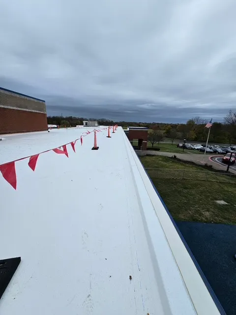 Edge of a white TPO roof with metal edge trim and a red safety flag line, from our Lebanon office's job photos