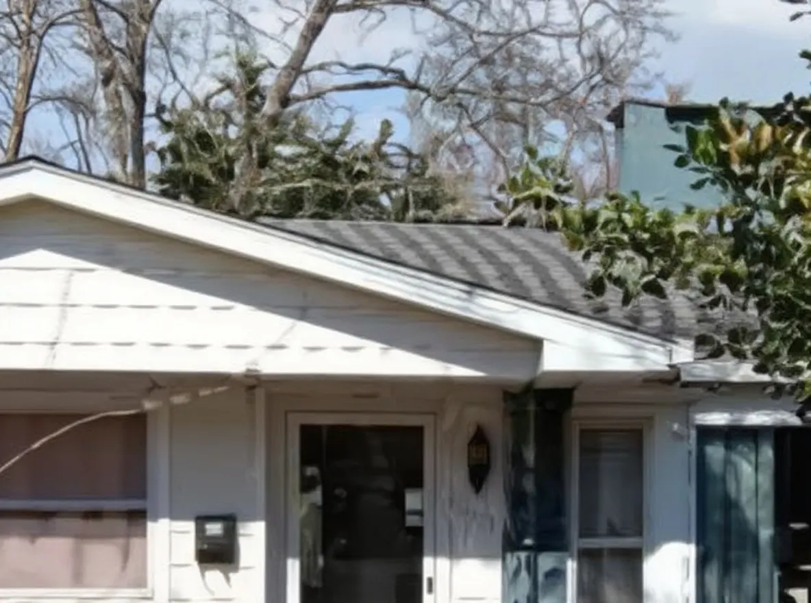 Single-story house with blue siding behind bare trees, Oak Ridge