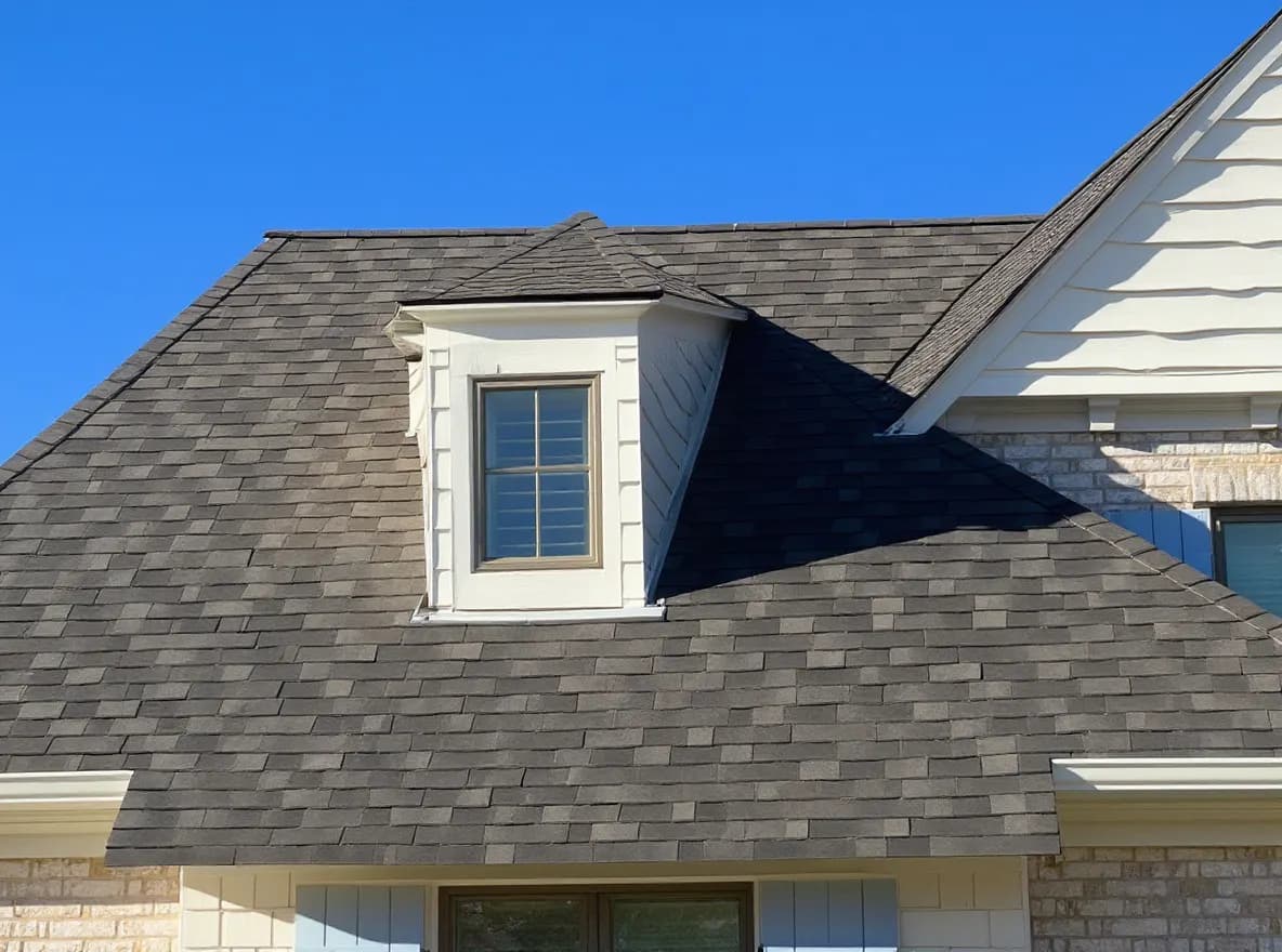 Closer view of the roof: a large two-story brick home with a newly installed gray shingle roof, multiple gables, and dormer windows under a clear blue sky