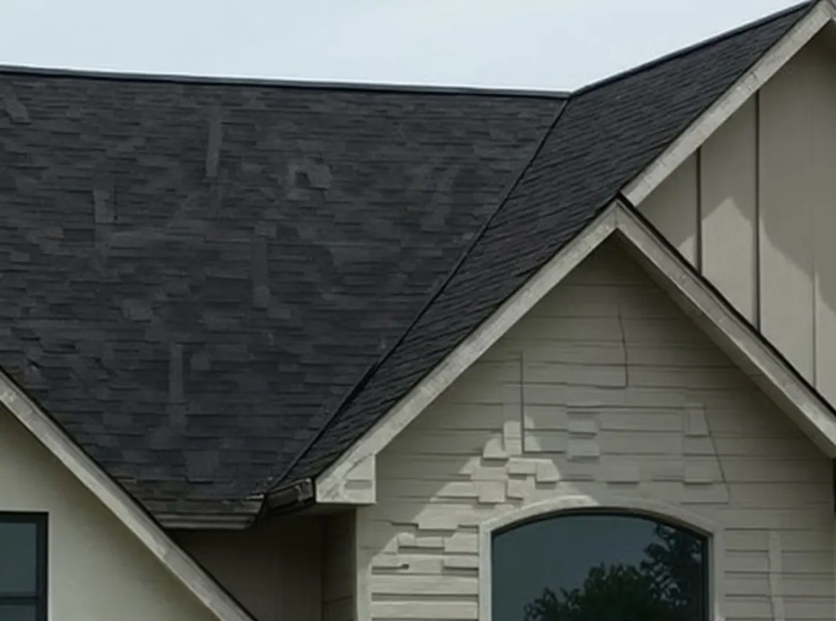 Closer view of the roof: a two-story house with a dark gray dimensional shingle roof and light-colored siding accented with dark trim